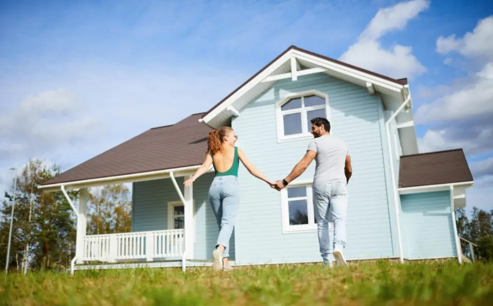 Couple walking toward a light blue house with a dark shingle roof