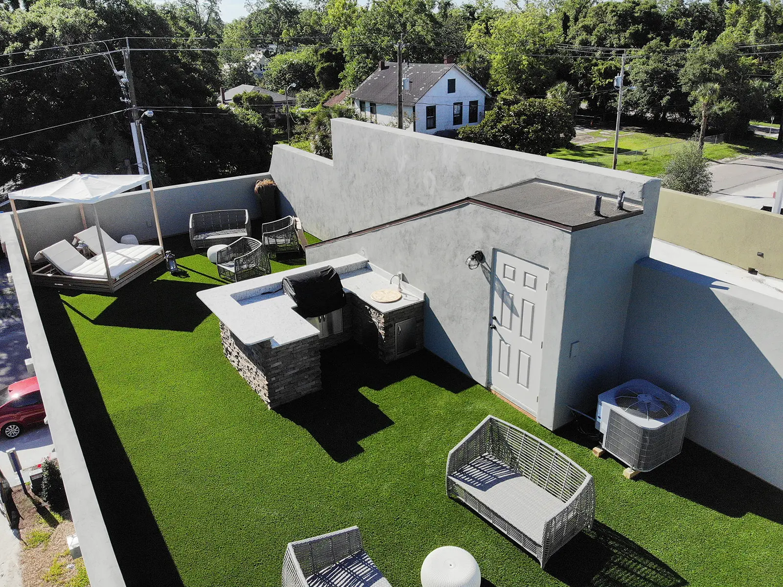 Waterproofed rooftop deck with turf, outdoor kitchen, and seating on a Jacksonville building