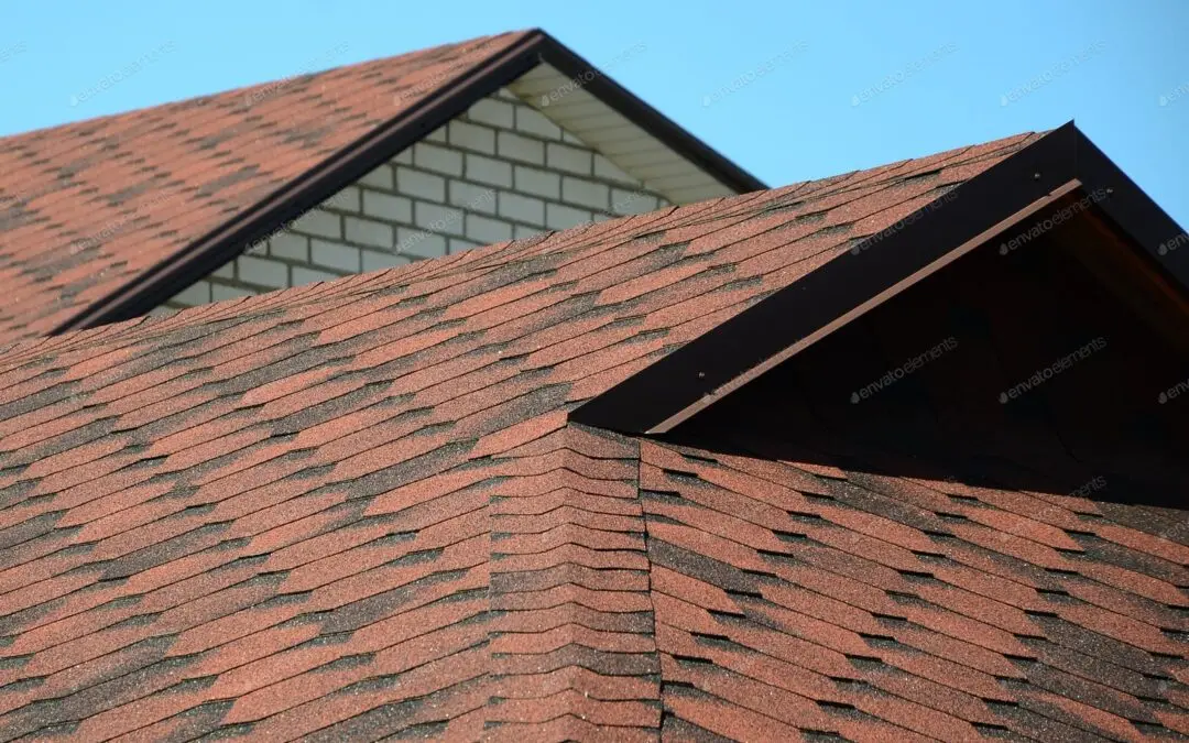 Brown asphalt shingle roof with gable ends against a blue sky
