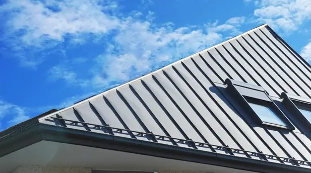 Standing seam metal roof with a skylight against a blue sky